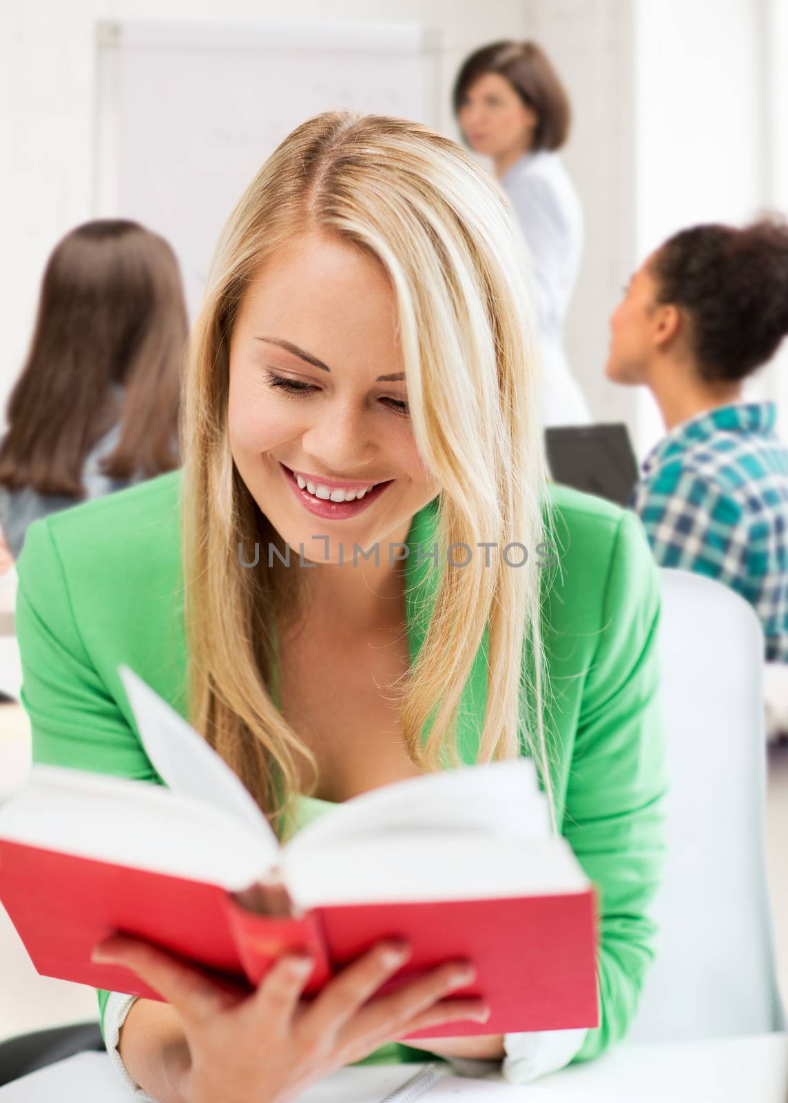 smiling student girl reading book at school by dolgachov