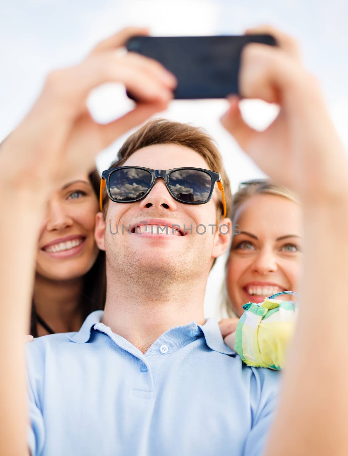 group of friends taking selfie with cell phone by dolgachov