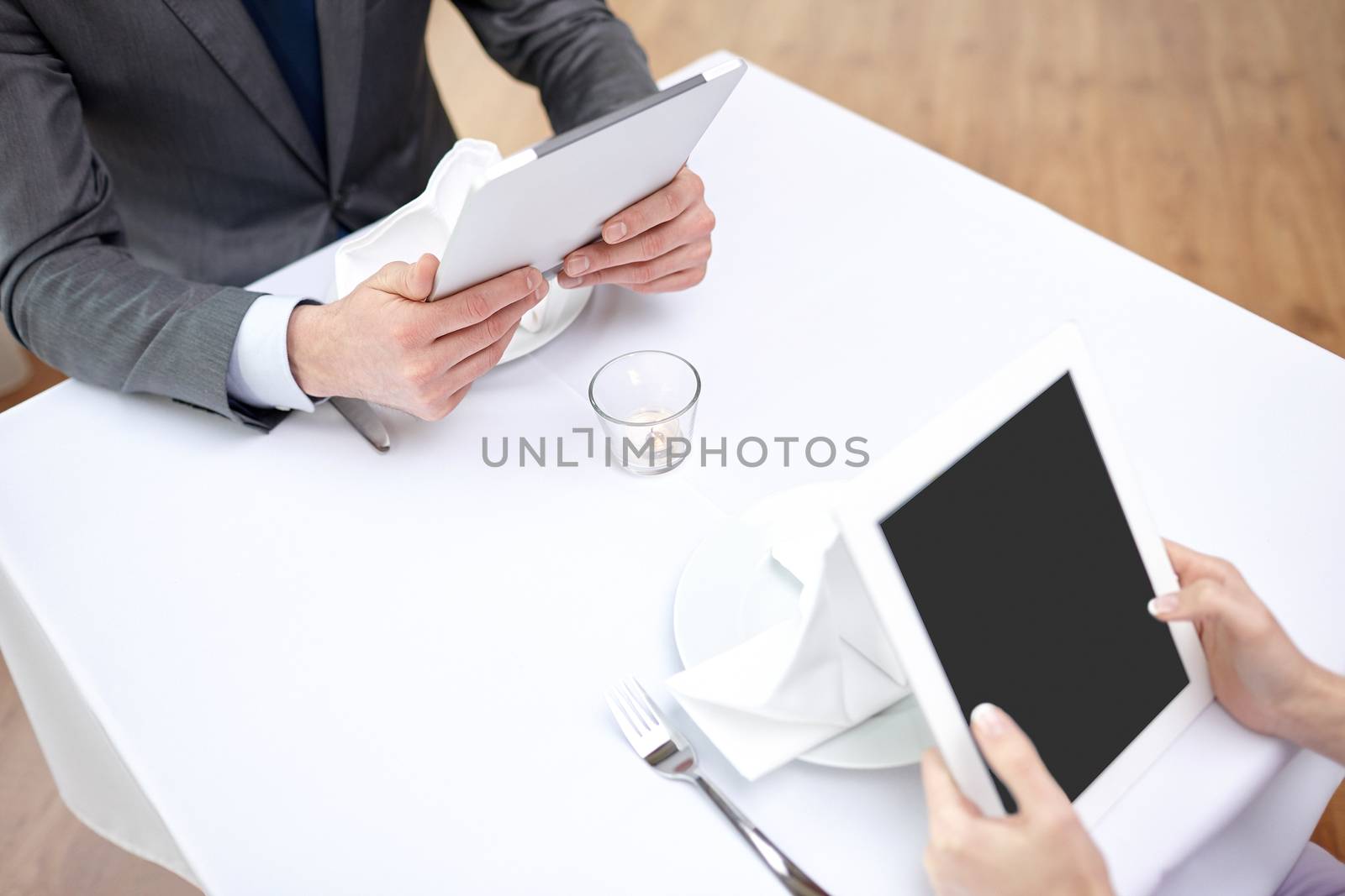 close up of couple with tablet pc at restaurant by dolgachov
