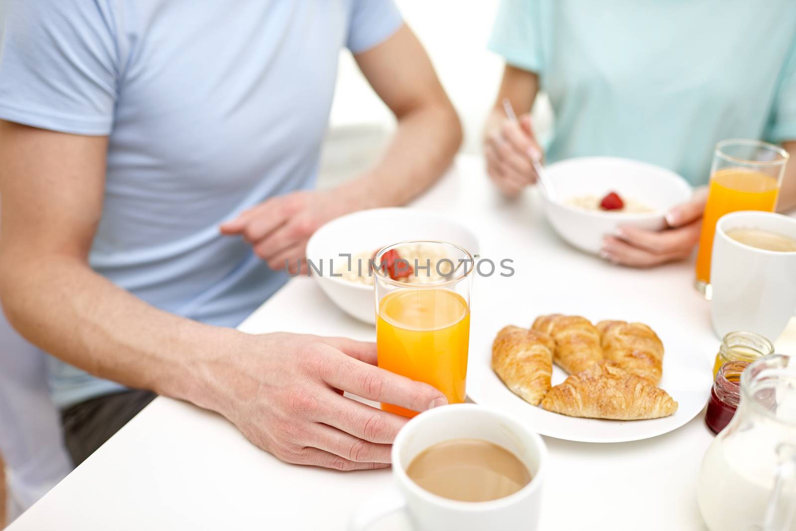 close up of couple having breakfast at home by dolgachov
