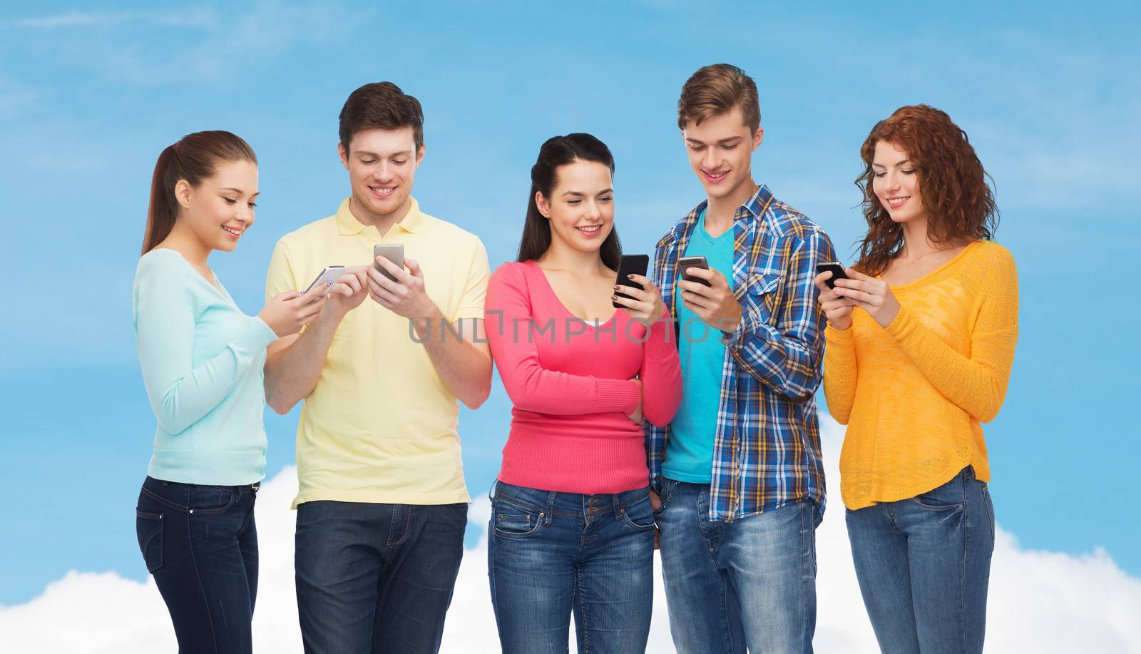 friendship, technology and people concept - group of smiling teenagers with smartphones over blue sky with white cloud background