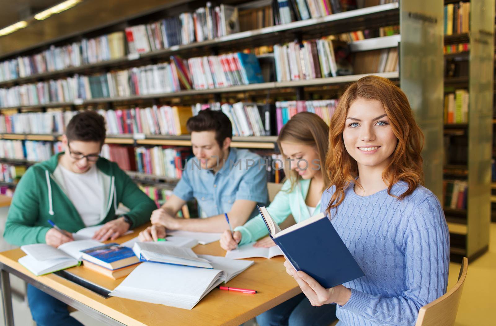 people, knowledge, education, literature and school concept - happy students reading books and preparing to exams in library