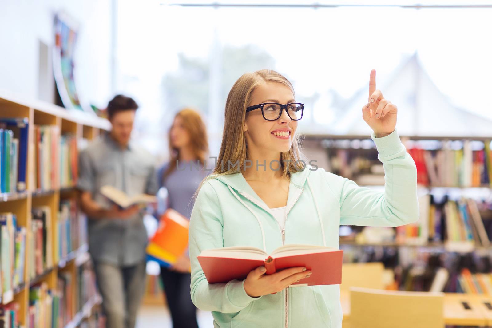 people, knowledge, education and school concept - happy student girl or young woman with book in library