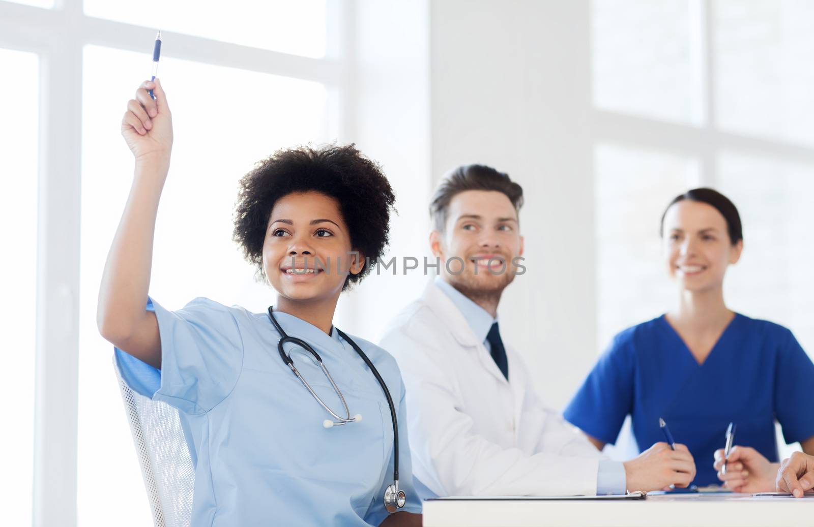 hospital, profession, people and medicine concept - group of happy doctors meeting and asking questions on conference at hospital