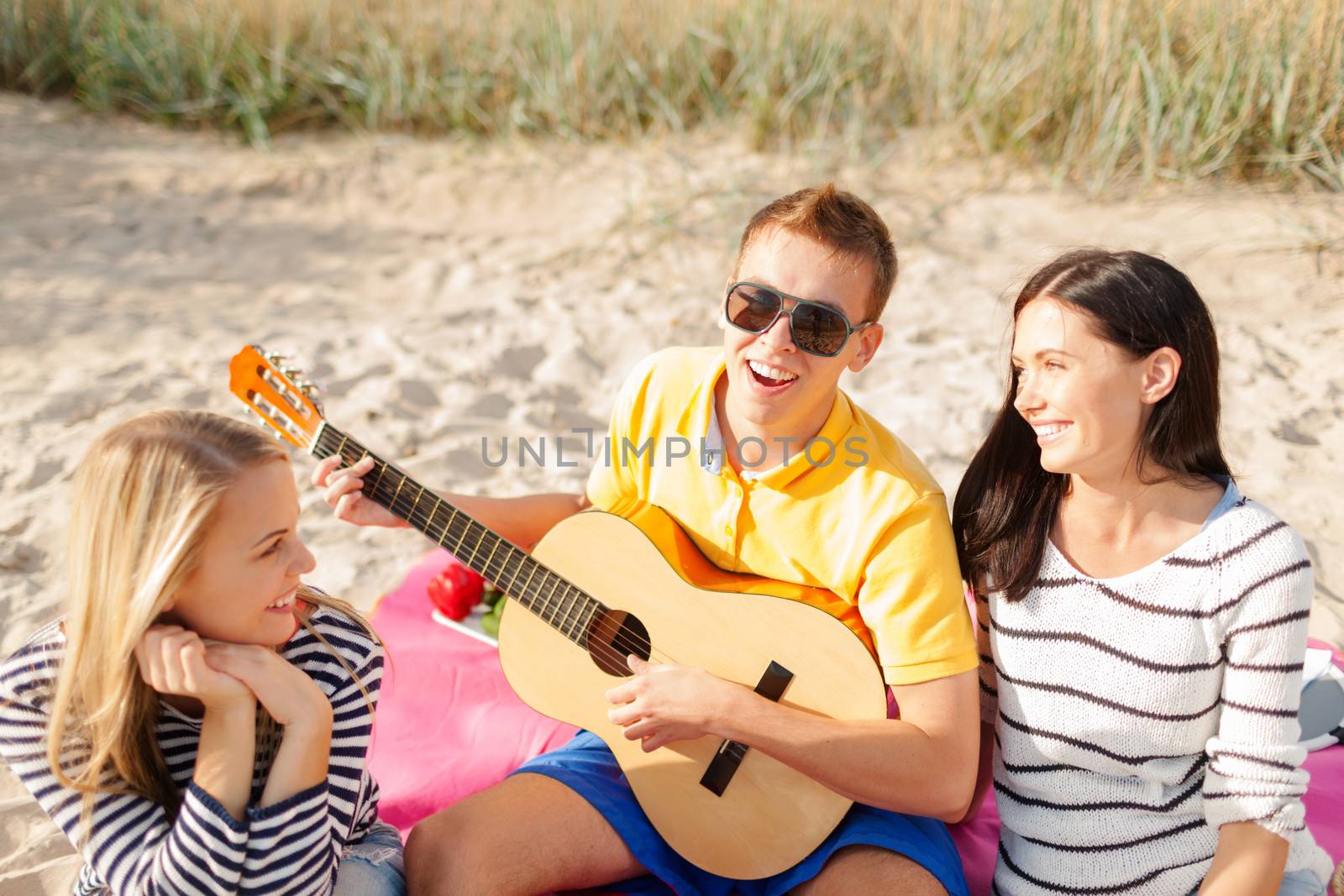 summer holidays, vacation, music, happy people concept - group of happy friends playing guitar on beach