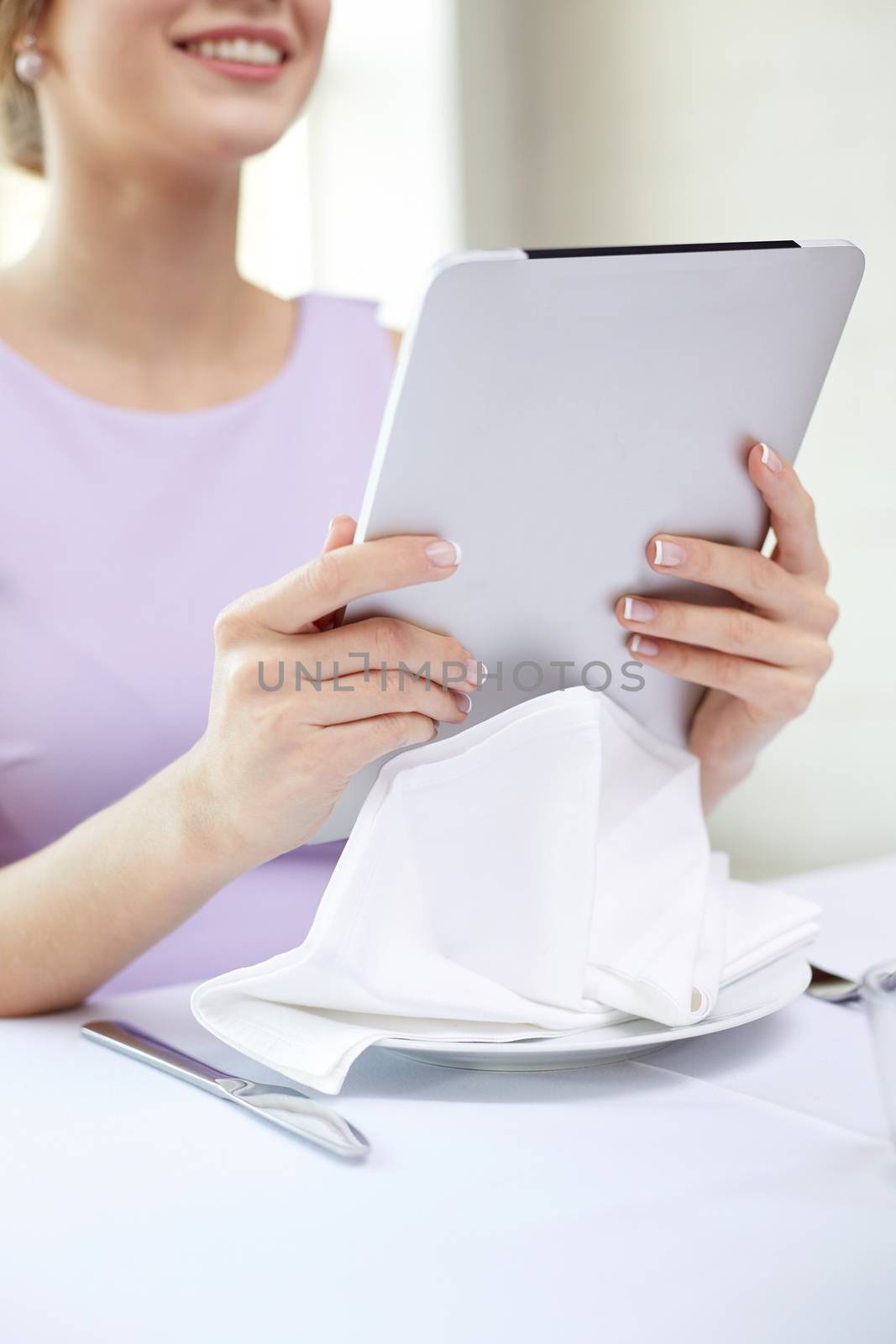 eating, technology and people concept - close up of young woman with tablet pc computer at restaurant