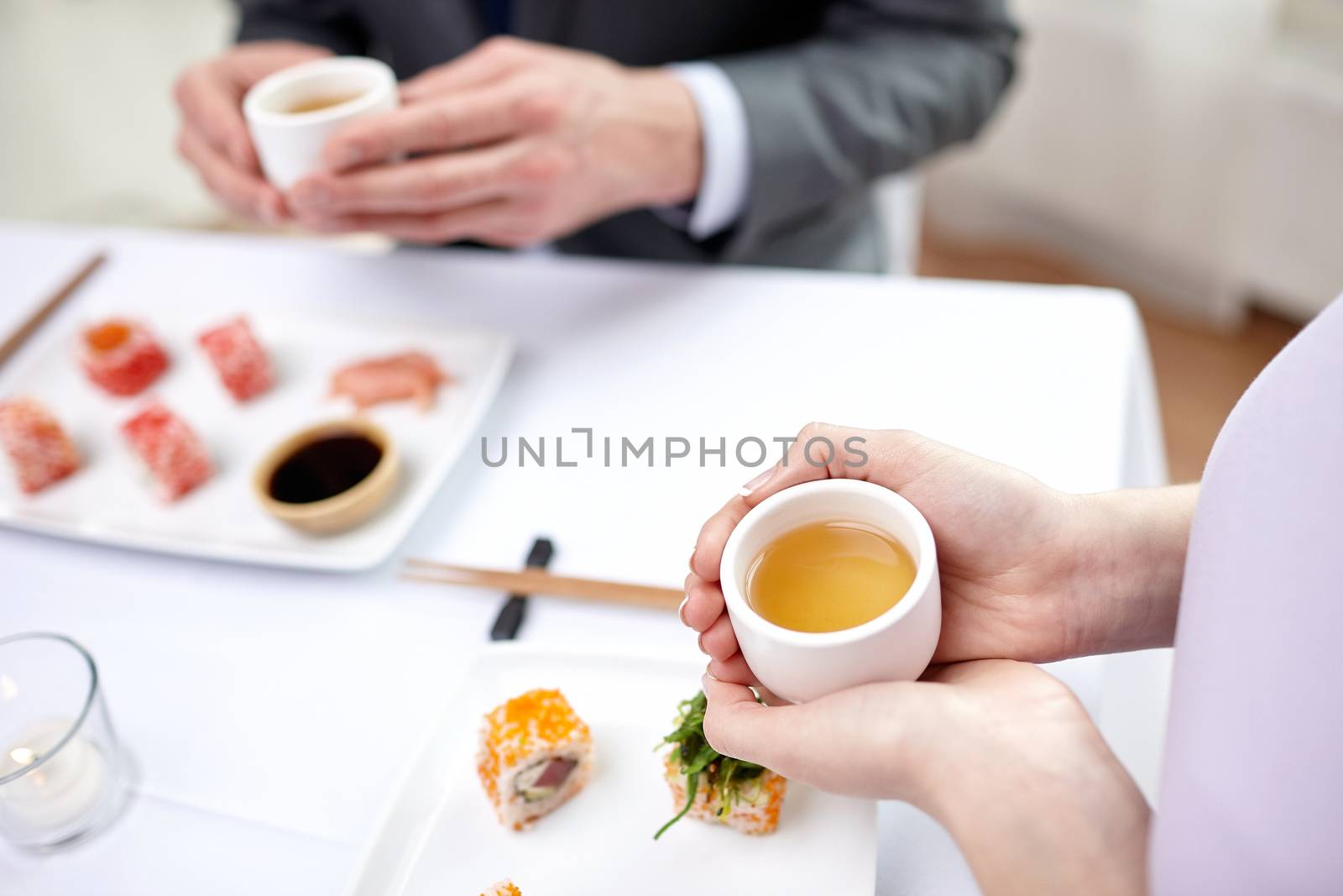 restaurant, food, people, japanese and asian kitchen concept - close up of couple drinking tea at restaurant
