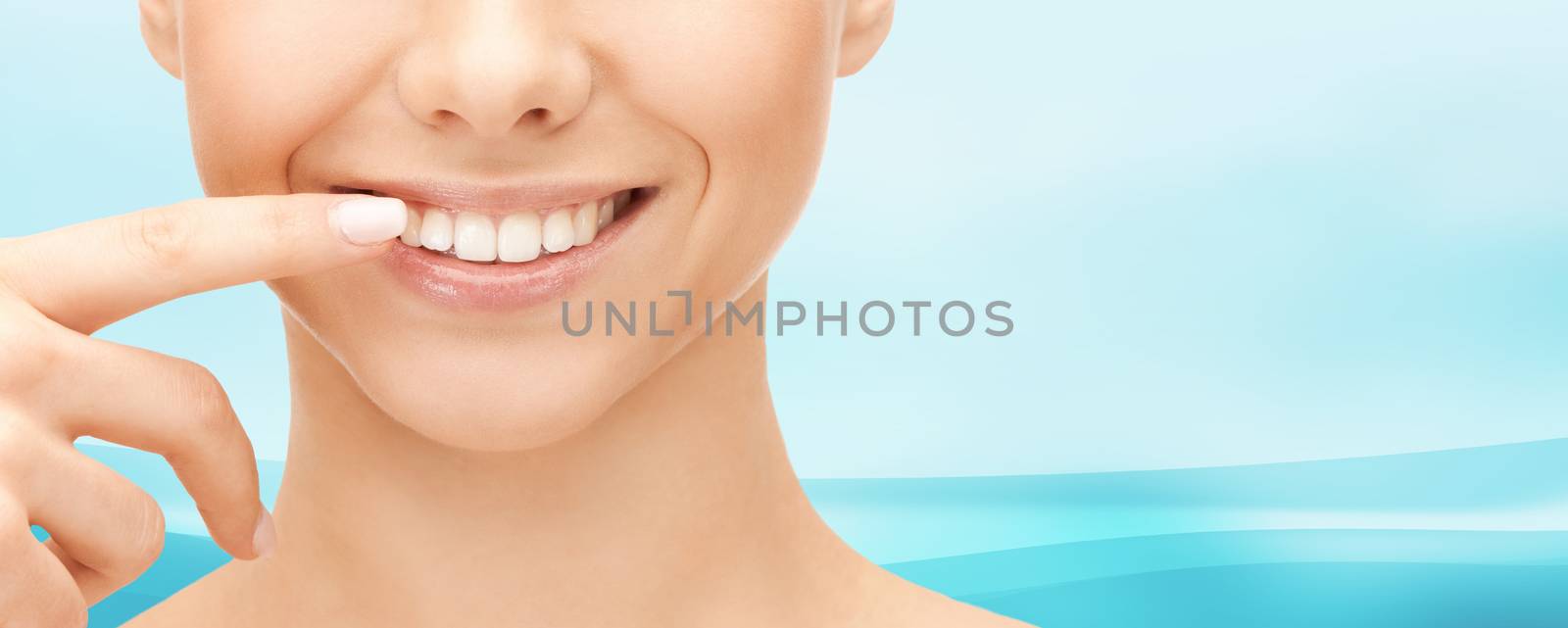 close up of smiling woman face pointing to teeth by dolgachov