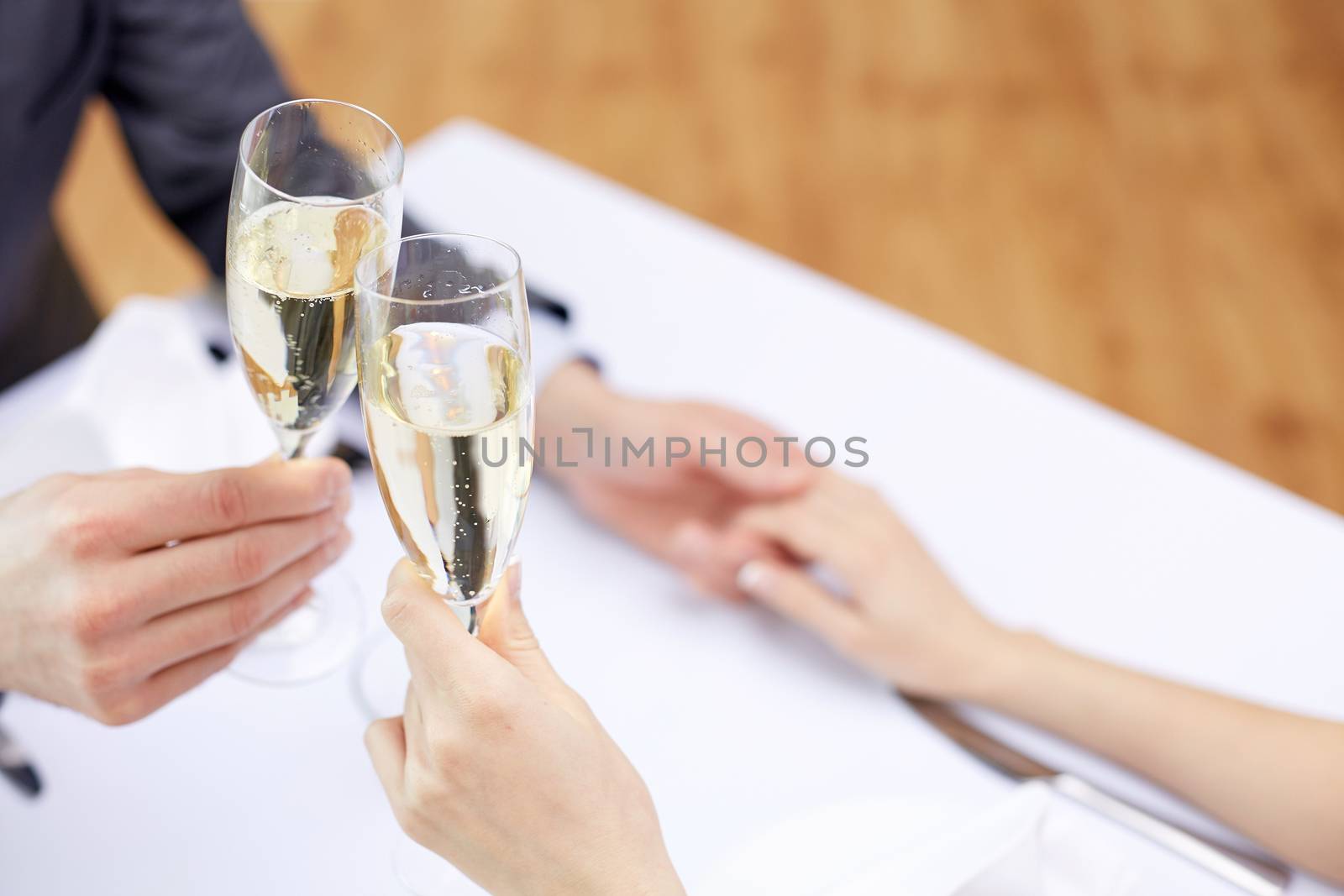 couple with glasses of champagne at restaurant by dolgachov