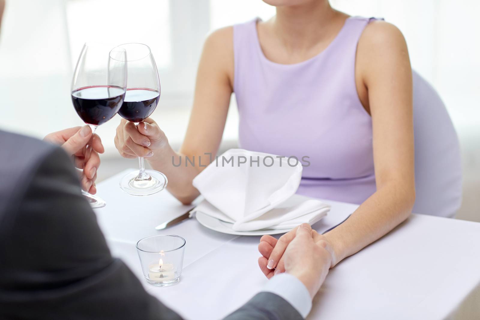 restaurant, people, celebration and holiday concept - close up of young couple with glasses of red wine at restaurant