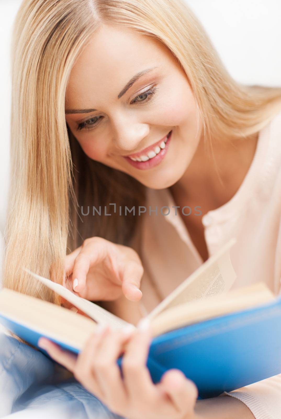 smiling woman lying on the sofa and reading book