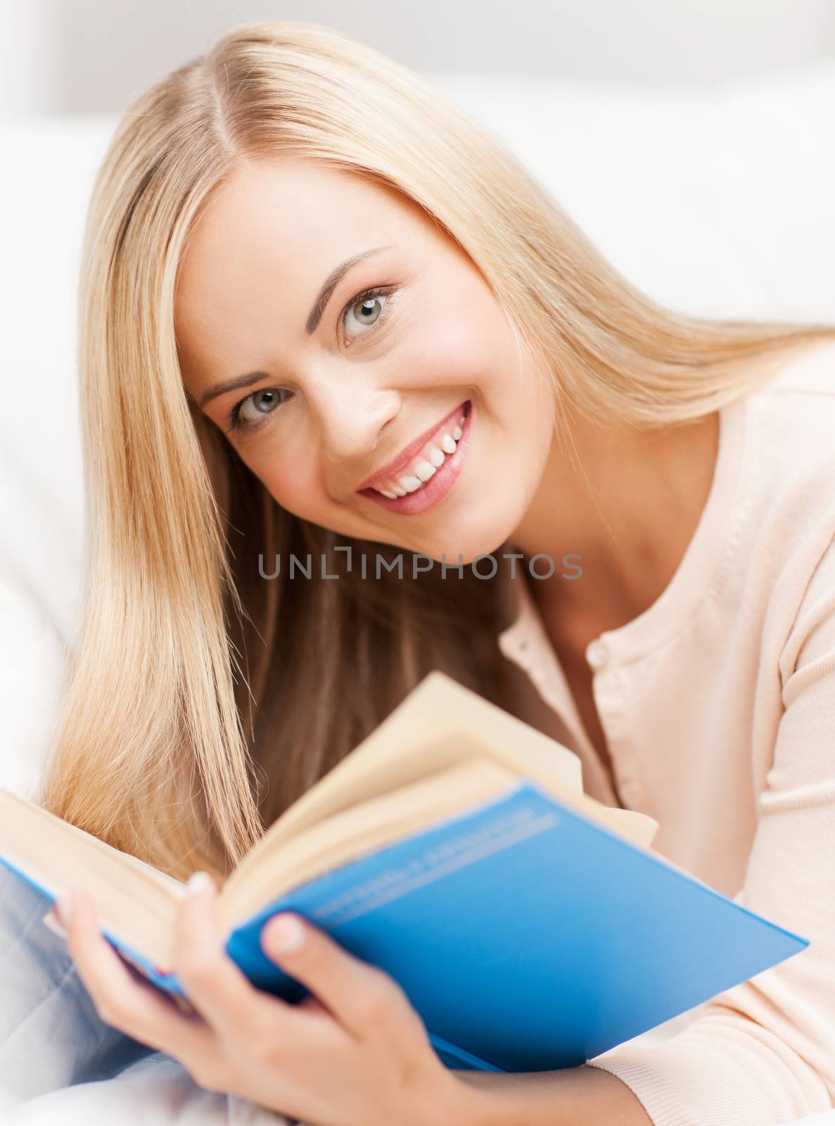 smiling woman lying on the sofa and reading book