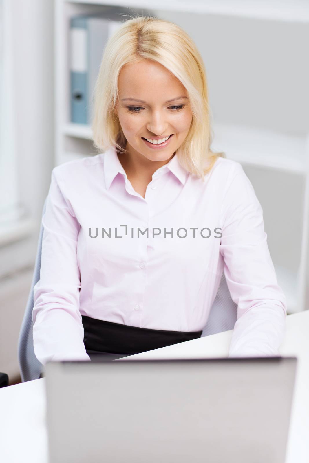 education, business and technology concept - smiling businesswoman or student with laptop computer in office