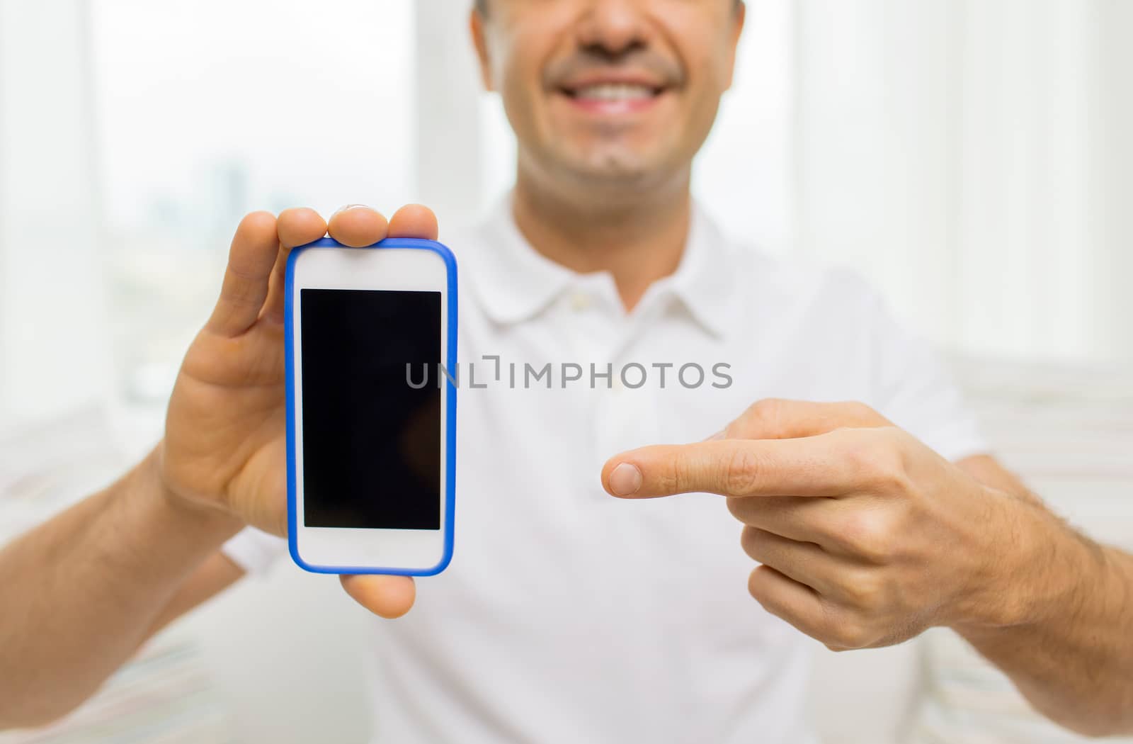 technology, people, lifestyle and communication concept - close up of happy man showing smartphone black blank screen at home