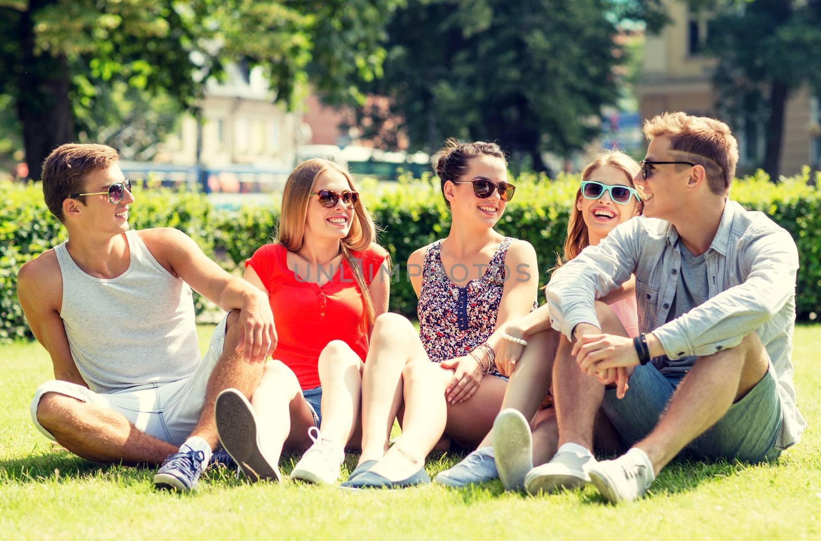 group of smiling friends outdoors sitting on grass by dolgachov