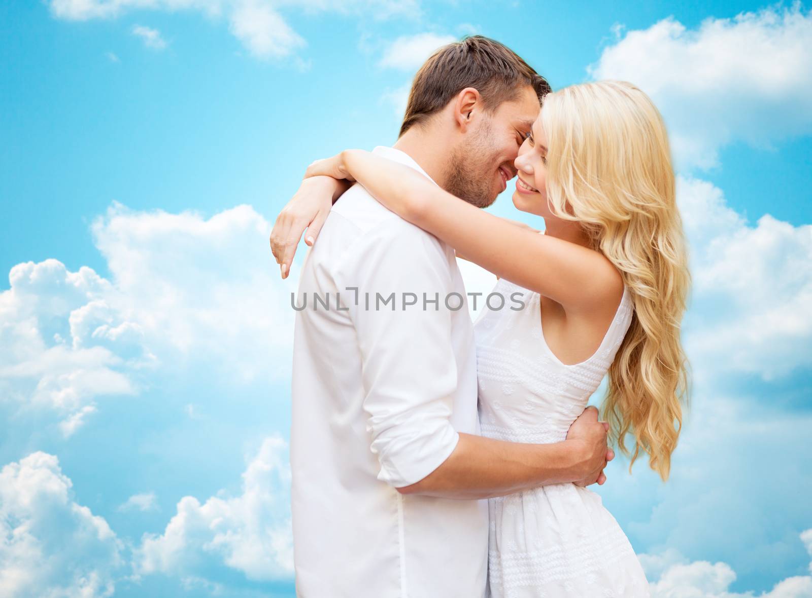 summer holidays, people, love and dating concept - happy couple hugging over blue sky and white clouds background