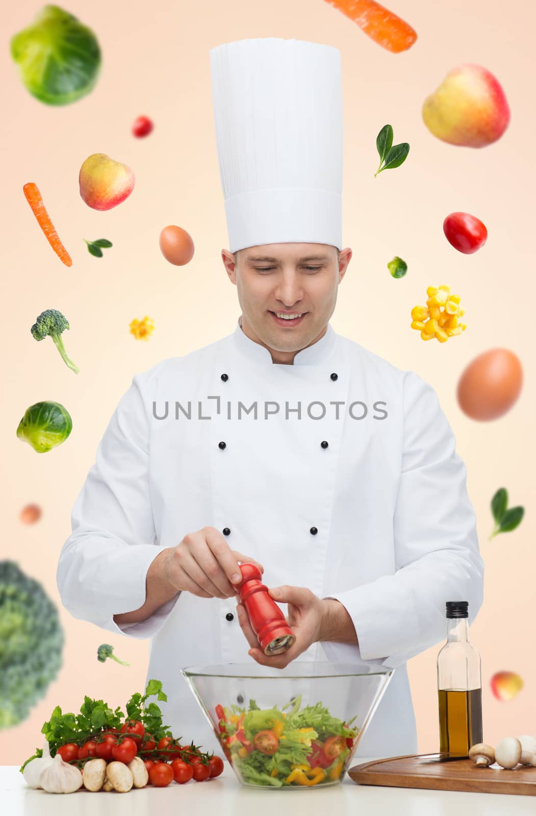 profession, vegetarian, food and people concept - happy male chef cooking and seasoning vegetable salad