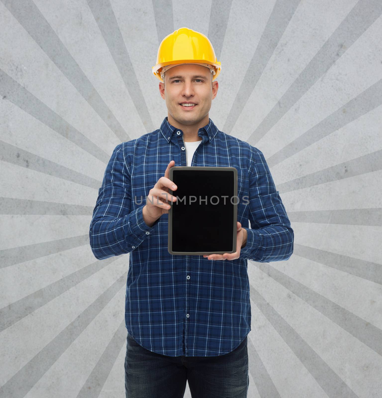 repair, construction, building, people and maintenance concept - smiling male builder or manual worker in helmet showing tablet pc computer blank screen over gray burst rays background
