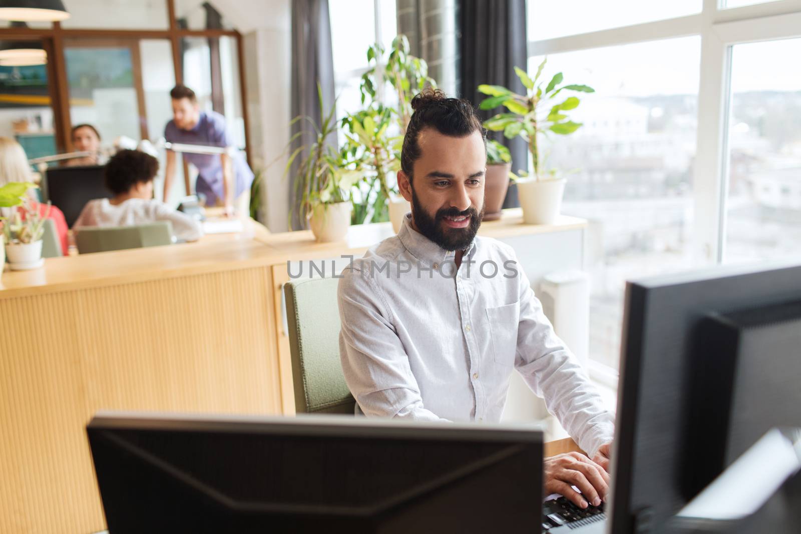 business, startup and people concept - happy businessman or creative male office worker with computer