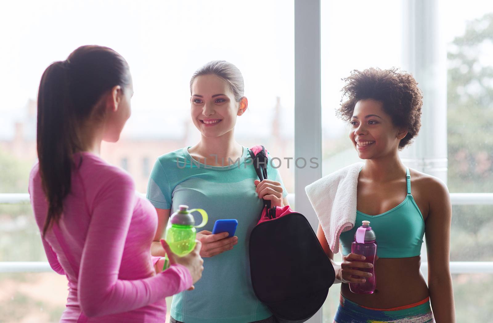 happy women with bottles of water in gym by dolgachov