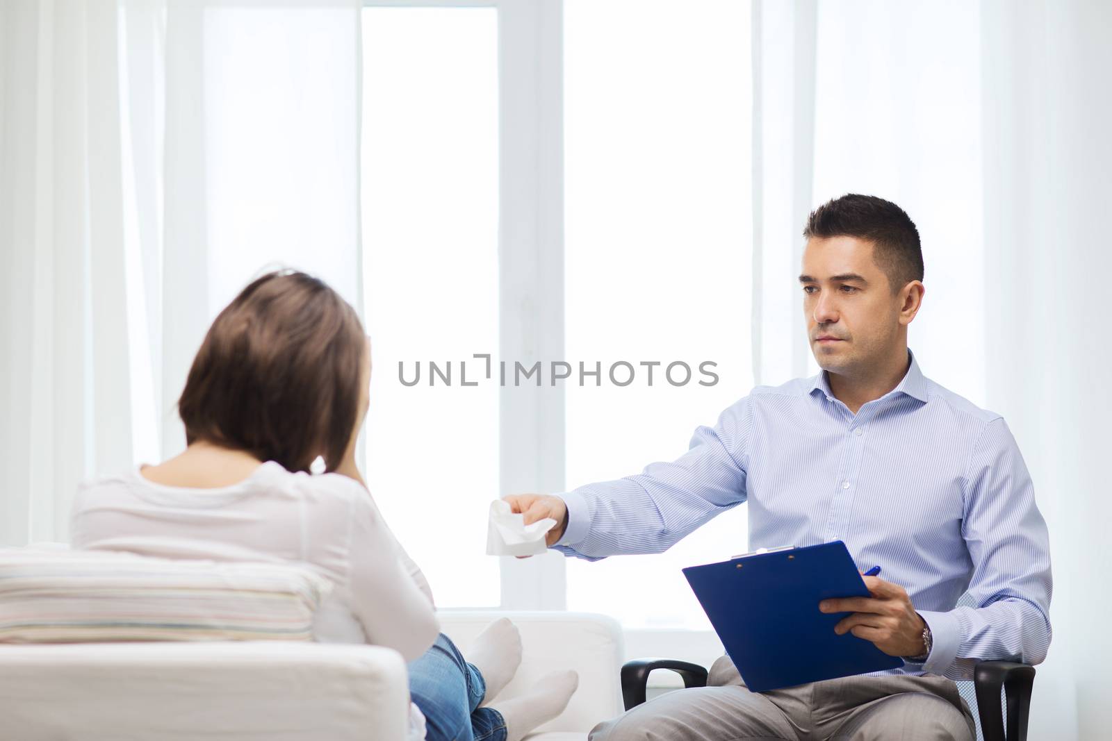 medicine, health care and people concept - doctor with clipboard and young woman meeting at home visit