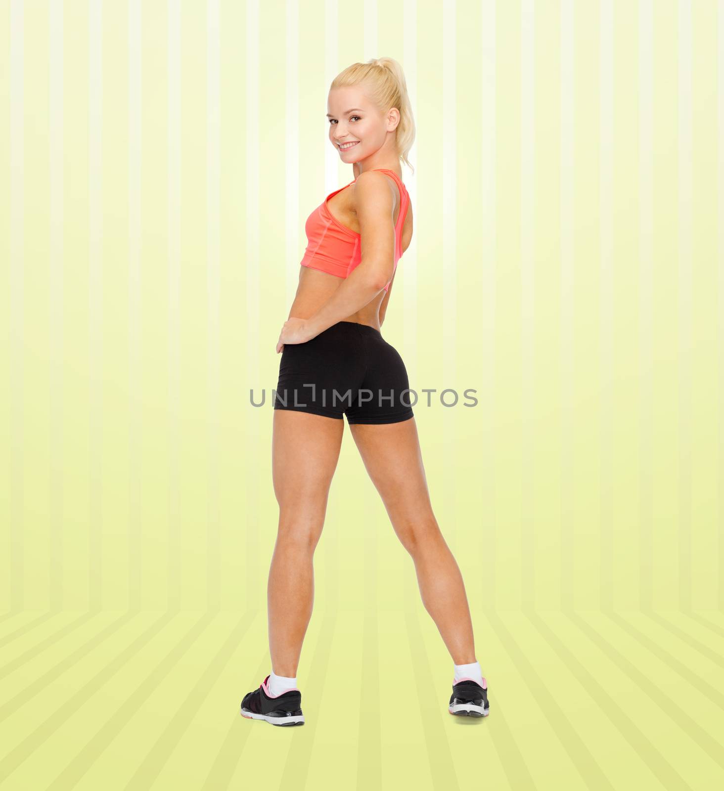 fitness, sport and people concept - beautiful athletic woman in sportswear from back over yellow striped background