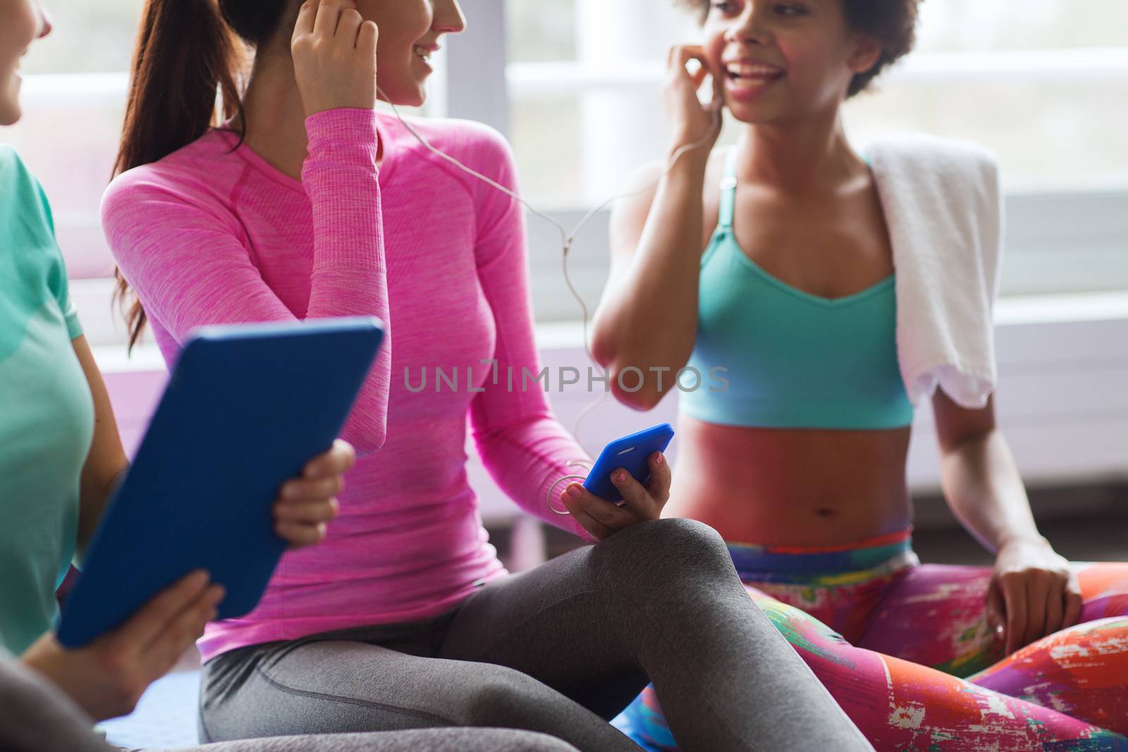 close up of happy women listening to music in gym by dolgachov