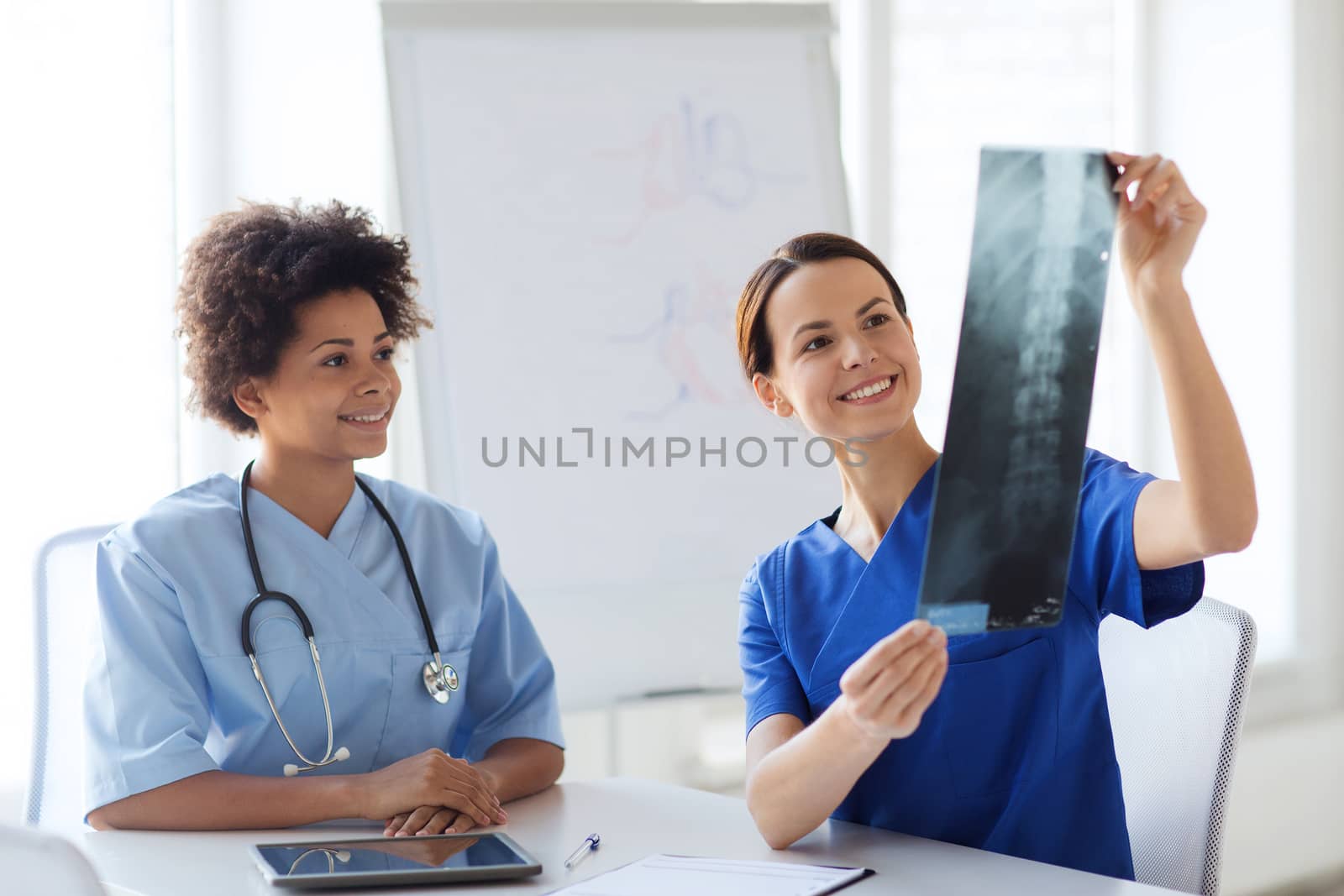 happy female doctors with x-ray image at hospital by dolgachov
