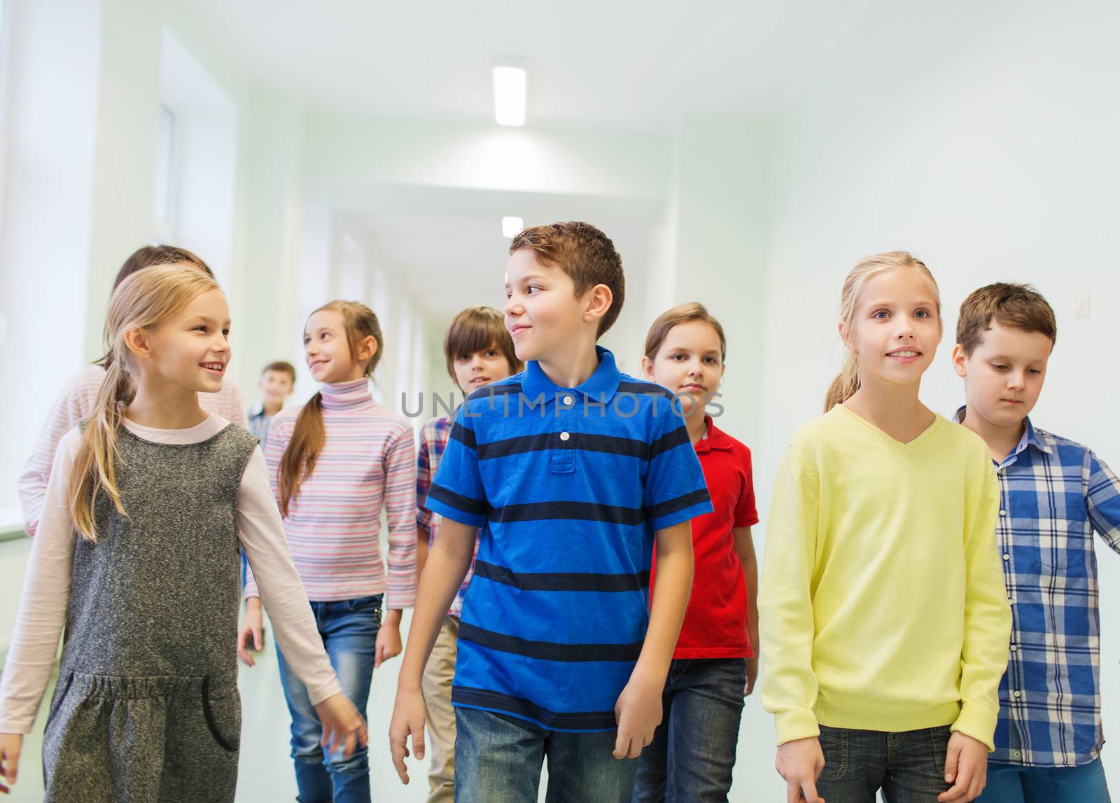 group of smiling school kids walking in corridor by dolgachov