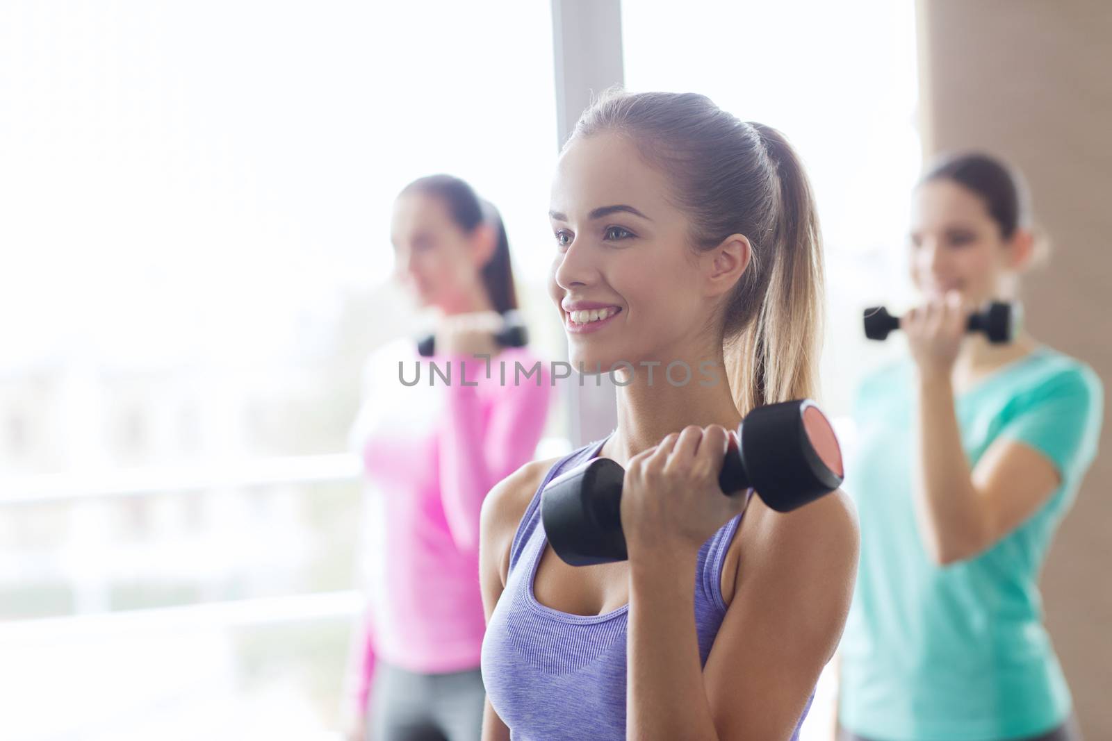 group of happy women with dumbbells in gym by dolgachov