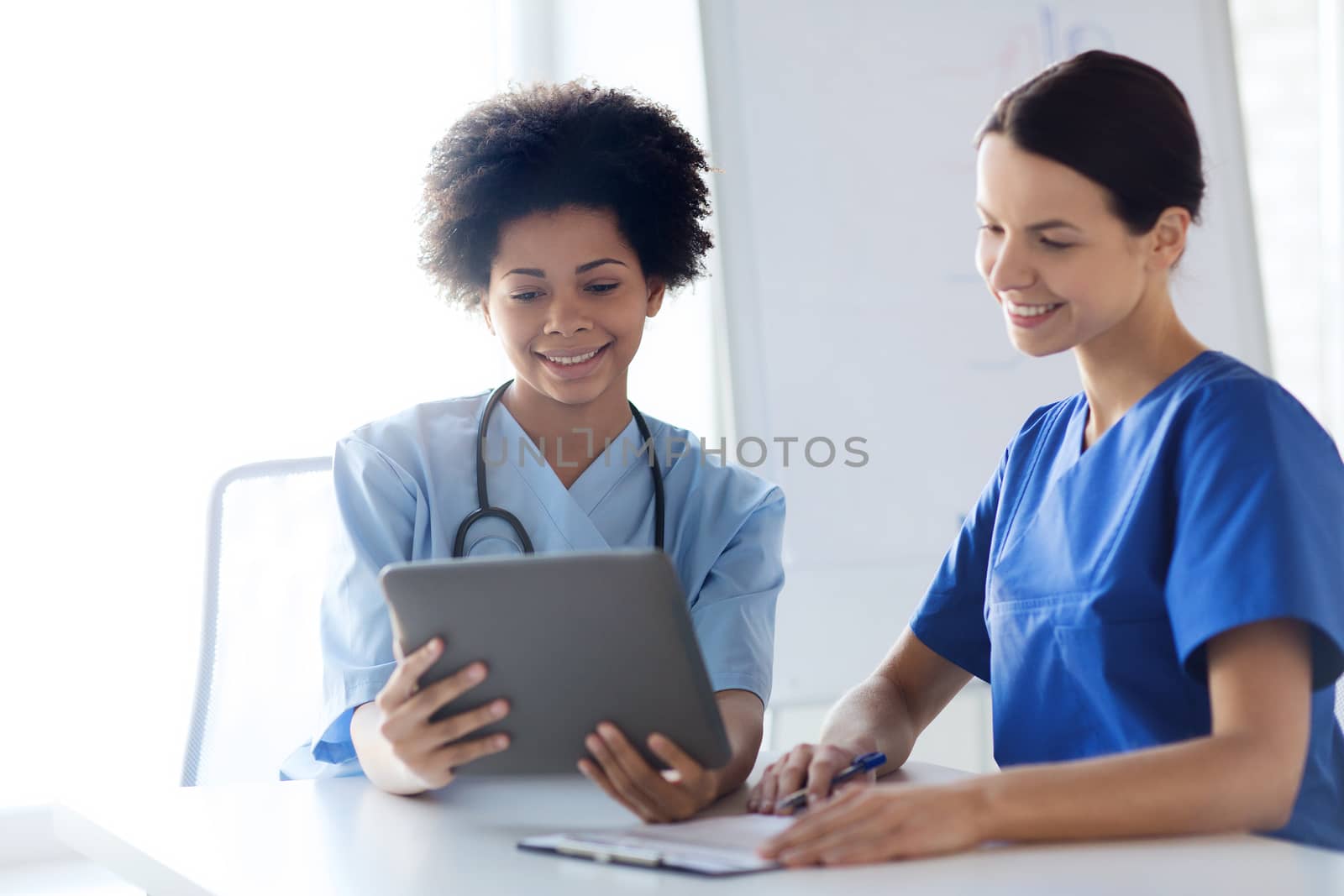 hospital, profession, people and medicine concept - group of happy doctors with tablet pc computer and clipboard meeting at medical office