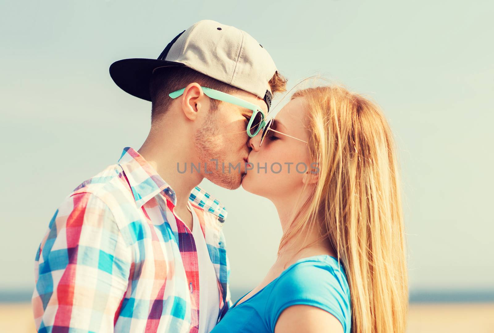 teenage couple kissing outdoors by dolgachov