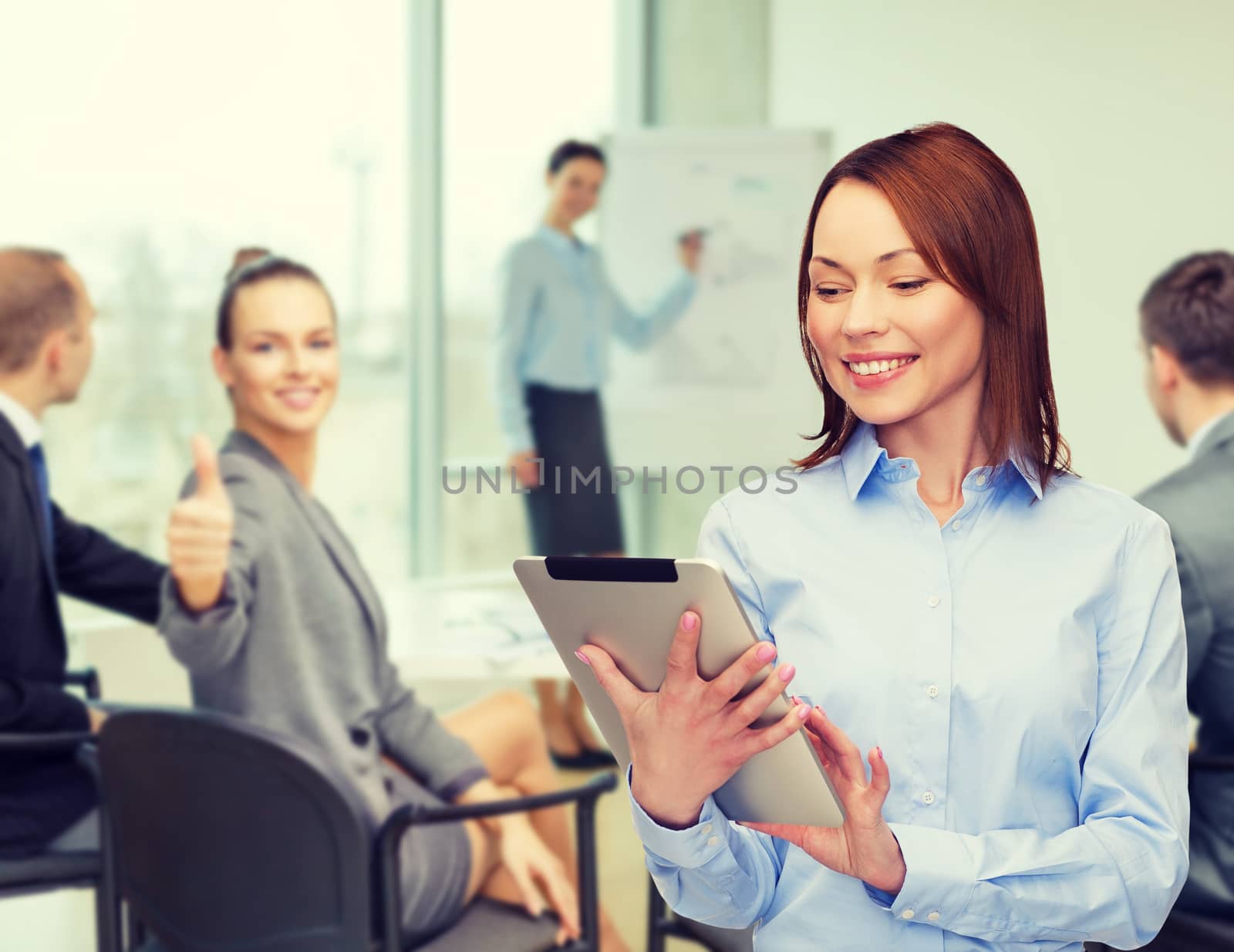 business, internet and technology concept - smiling woman looking at tablet pc computer at office