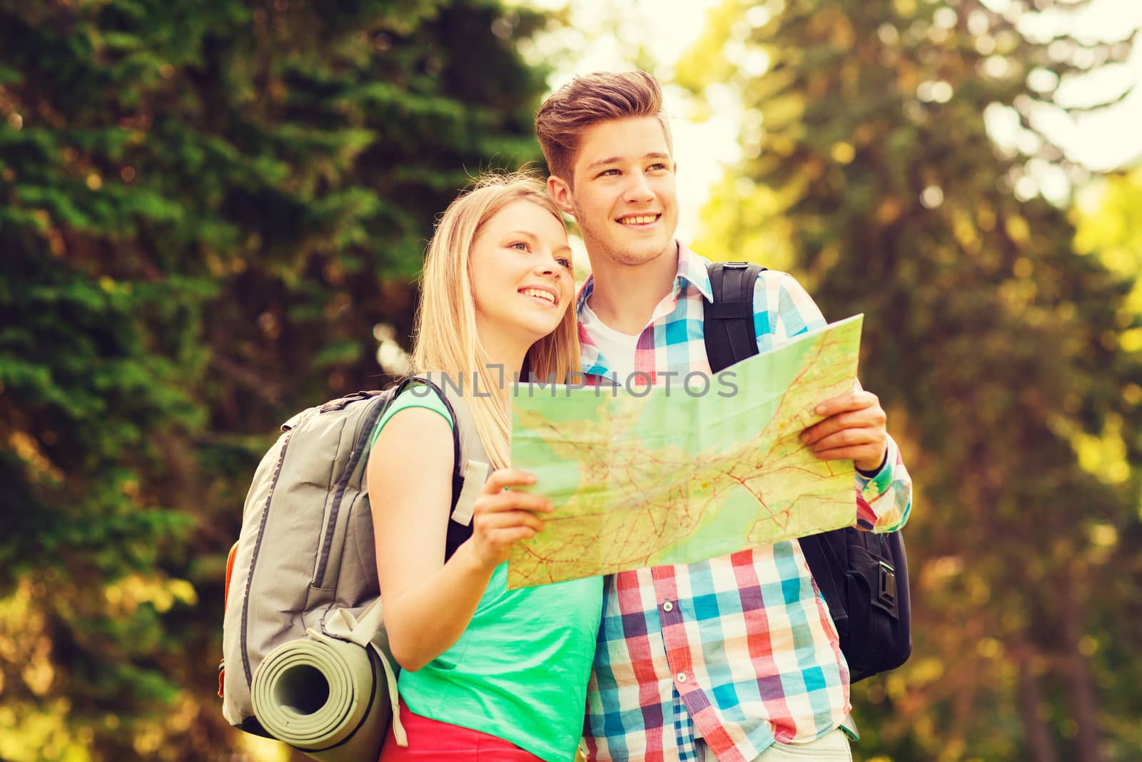 smiling couple with map and backpack in forest by dolgachov