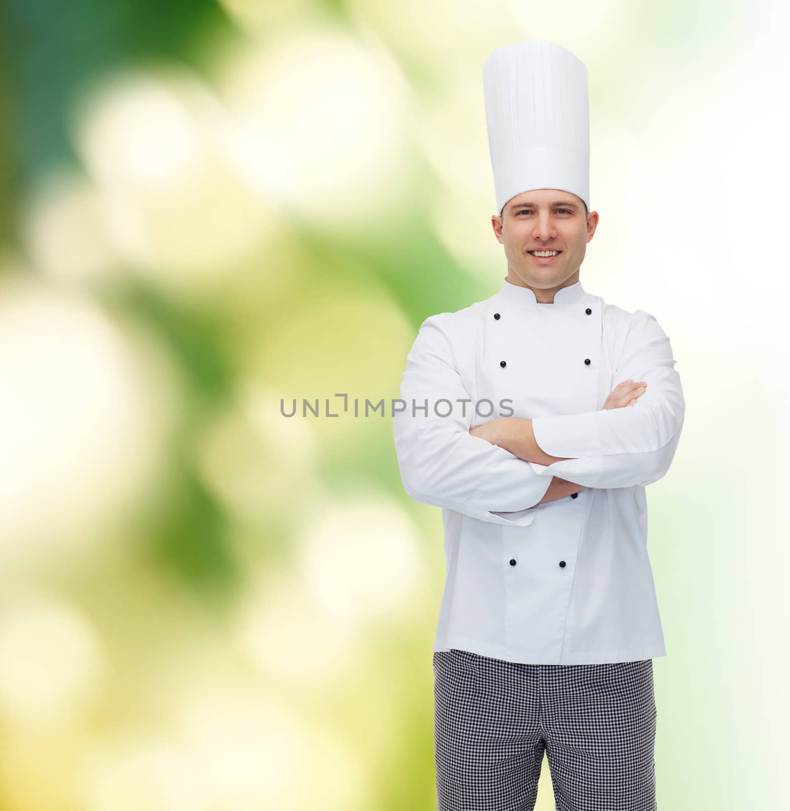 cooking, profession and people concept - happy male chef cook with crossed hands over green background