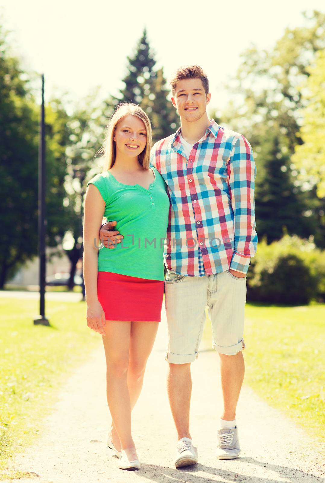 holidays, vacation, love and friendship concept - smiling couple walking in park