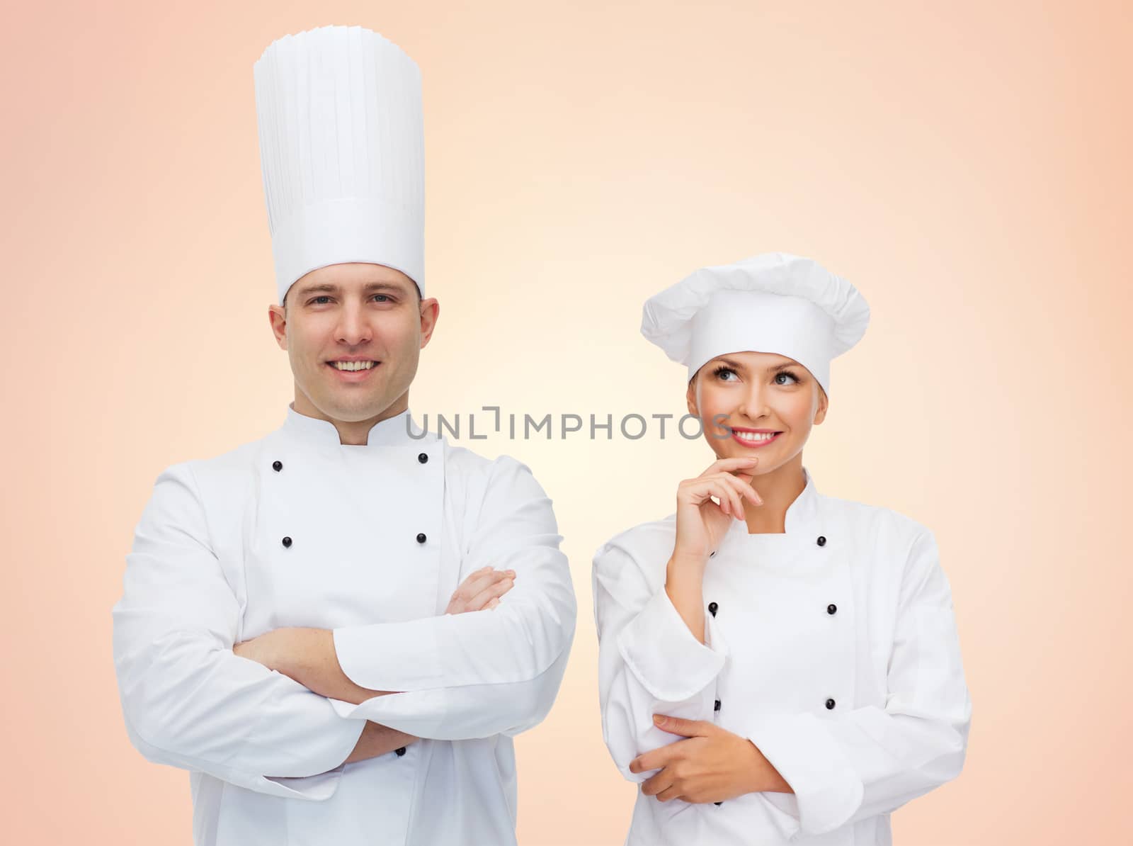 cooking, profession, teamwork and people concept - happy chefs or cooks couple over beige background