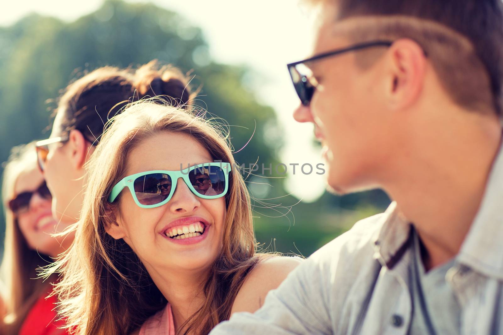 group of smiling friends sitting on city street by dolgachov