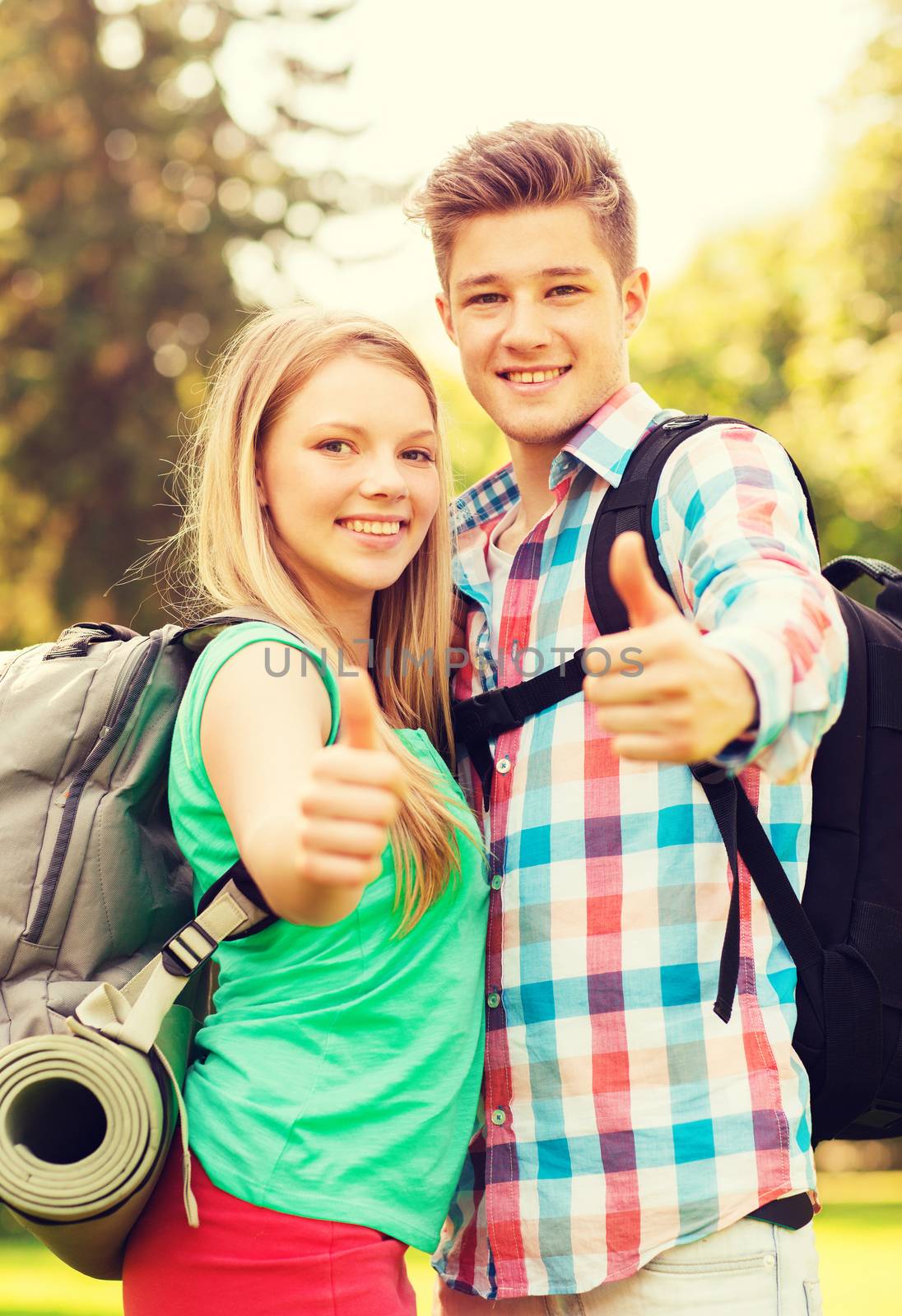 travel, vacation, tourism, gesture and friendship concept - smiling couple with backpacks showing thumbs up in nature