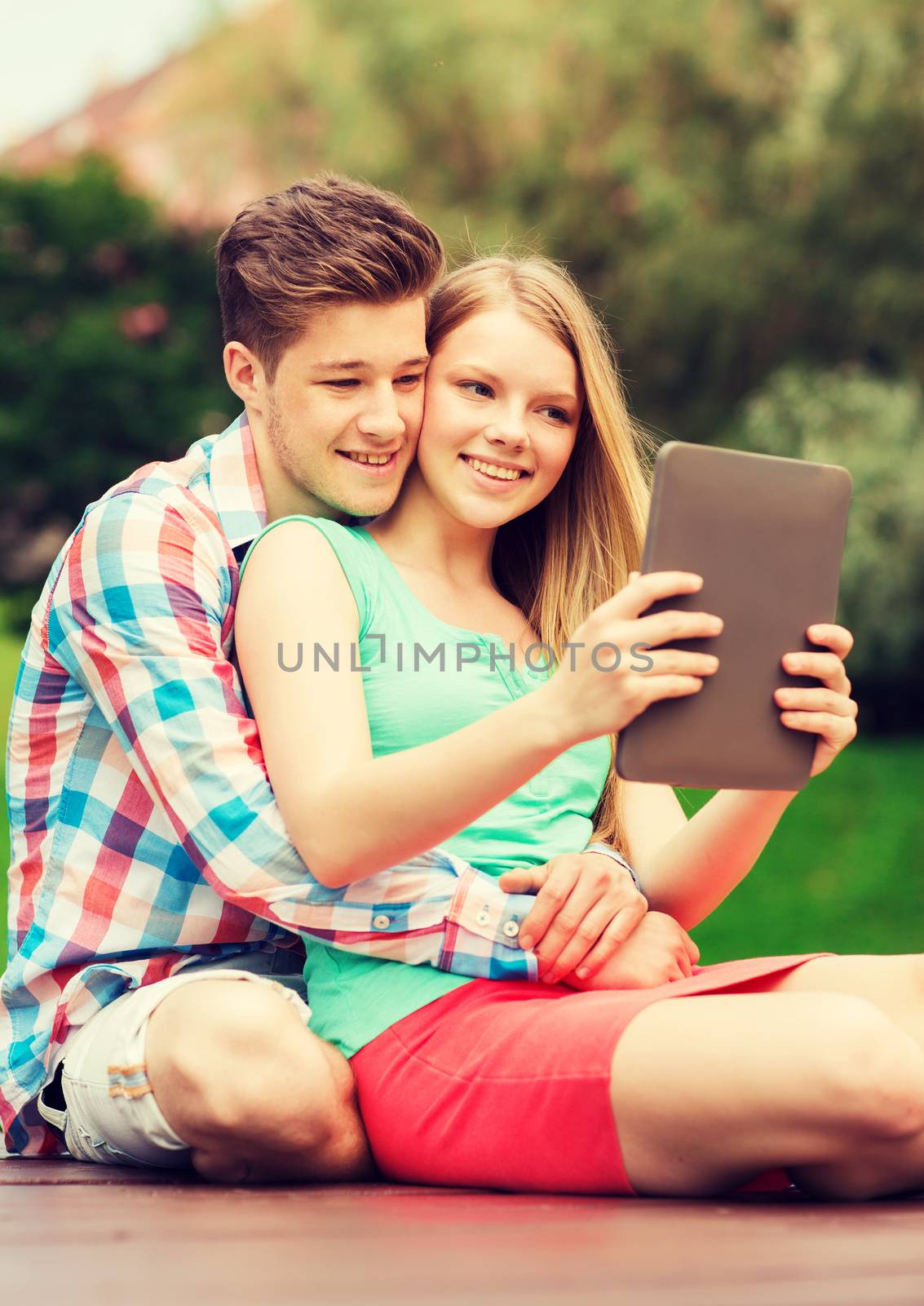 vacation, holidays, technology and friendship concept - smiling couple with tablet pc computer making selfie in park