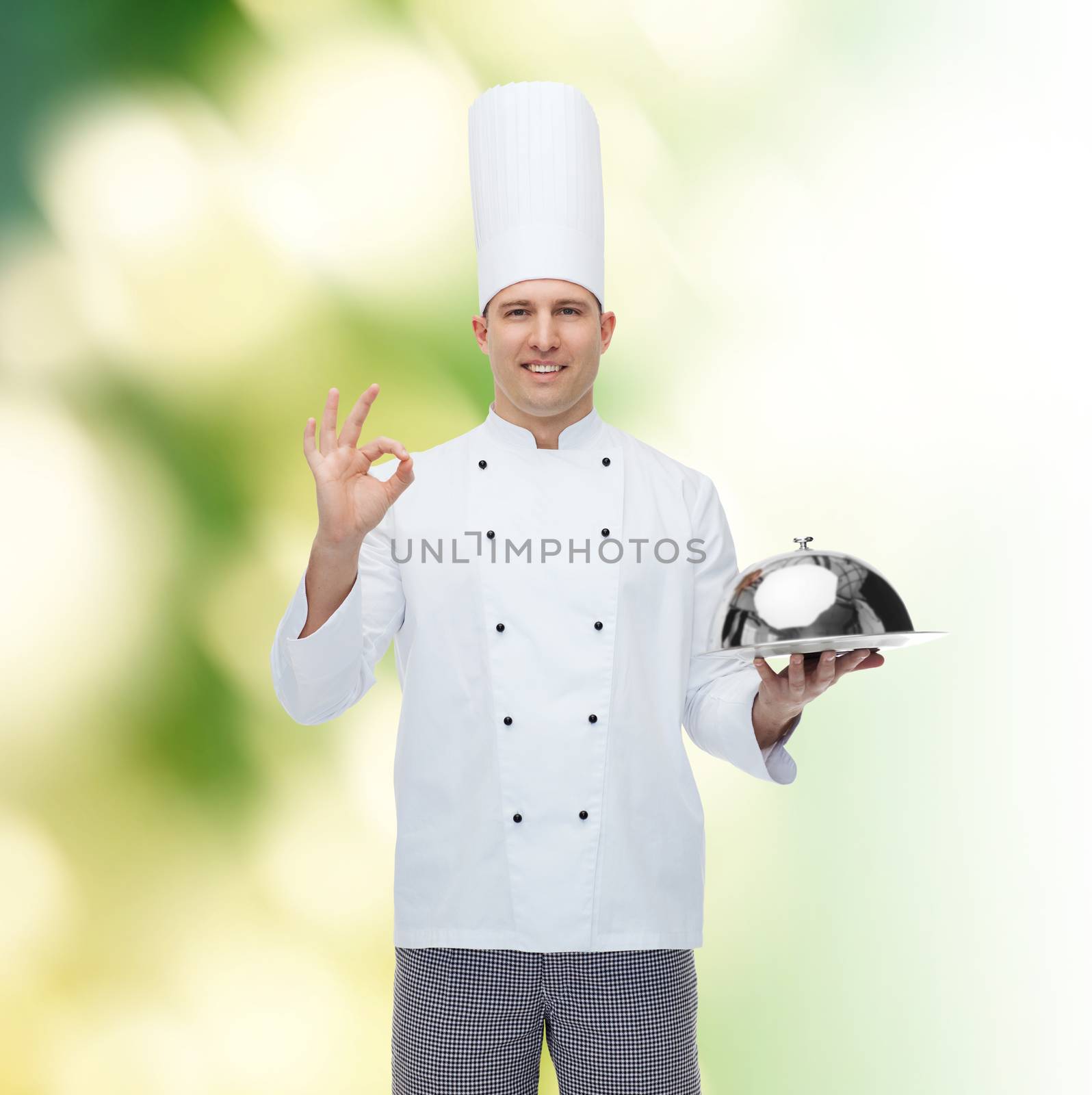 cooking, profession, gesture and people concept - happy male chef cook holding cloche and showing ok sign over green background