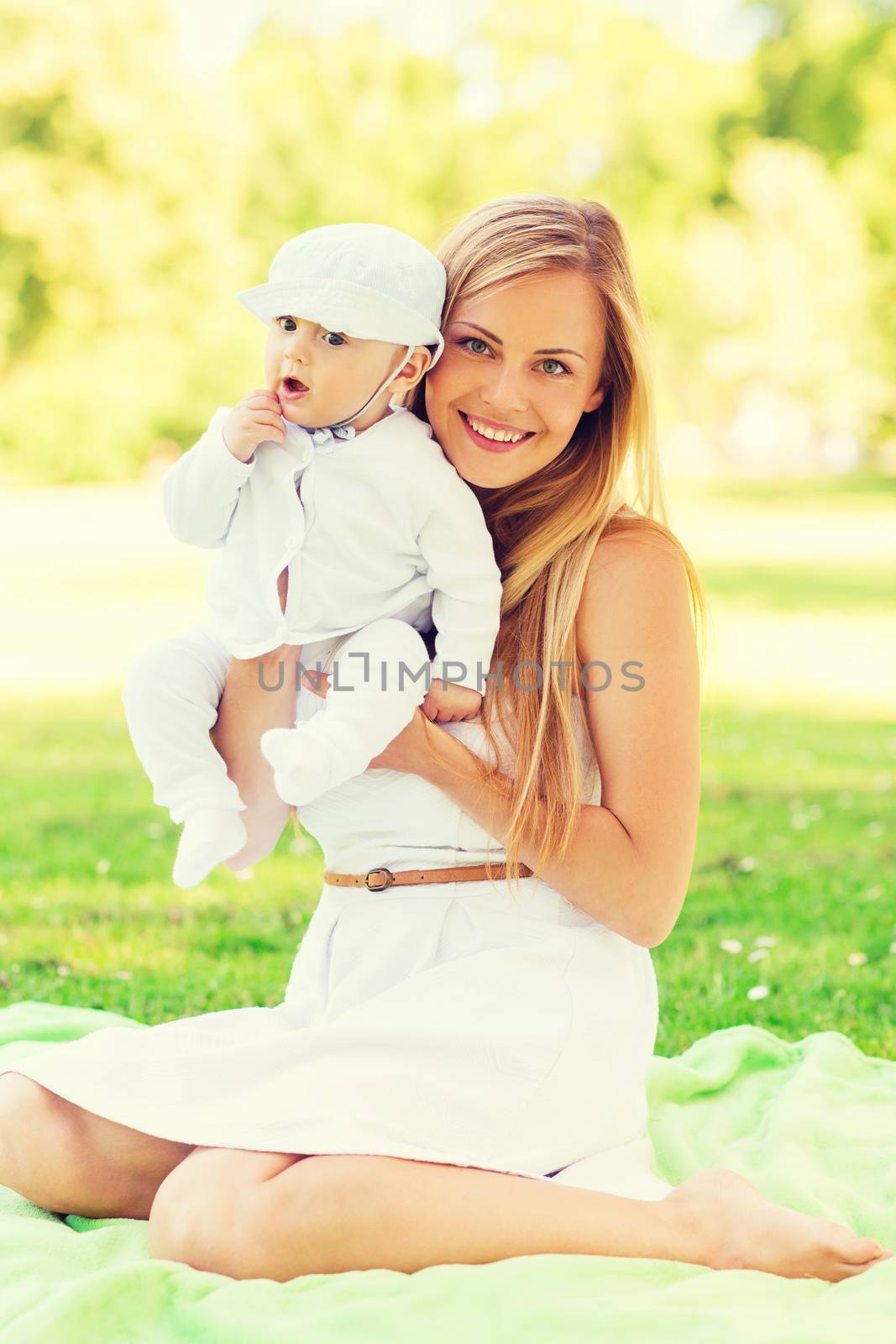 happy mother with little baby sitting on blanket by dolgachov