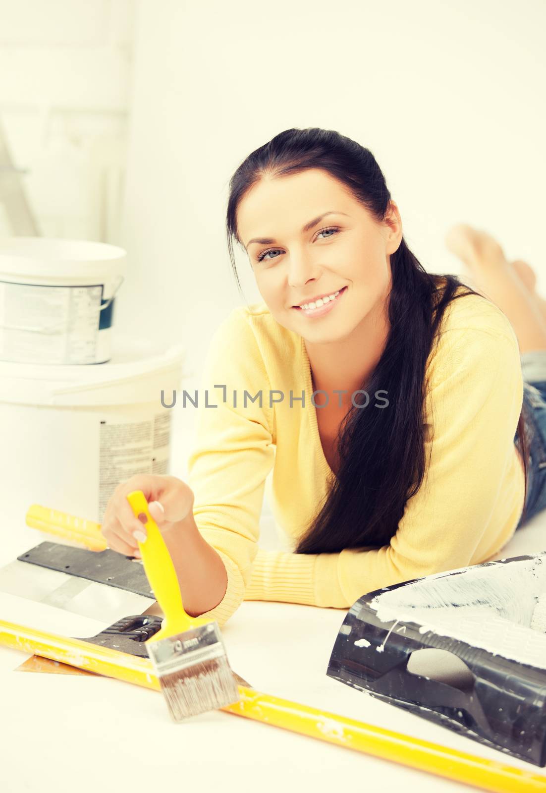 happy young woman with paintbrush and renovating tools