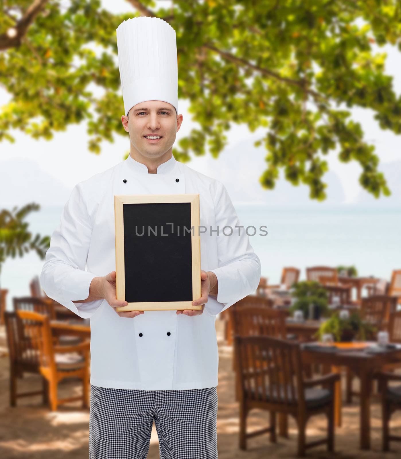 happy male chef cook holding blank menu board by dolgachov