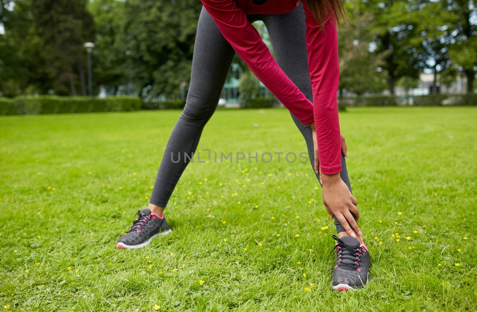close up of woman stretching leg outdoors by dolgachov