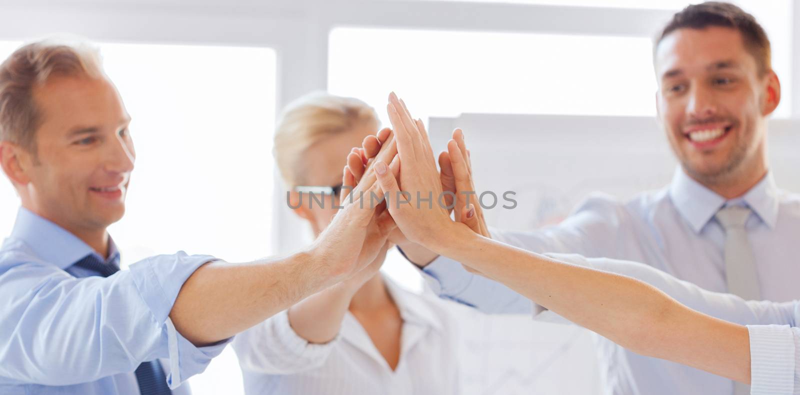 happy business team giving high five in office by dolgachov