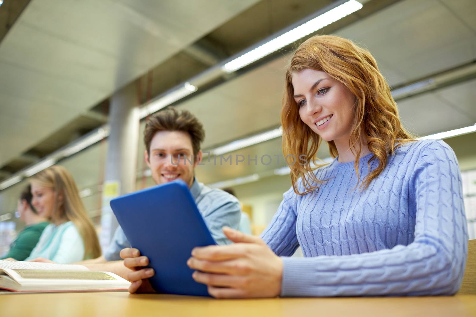 people, education, technology and school concept - happy students with tablet pc computer networking in library