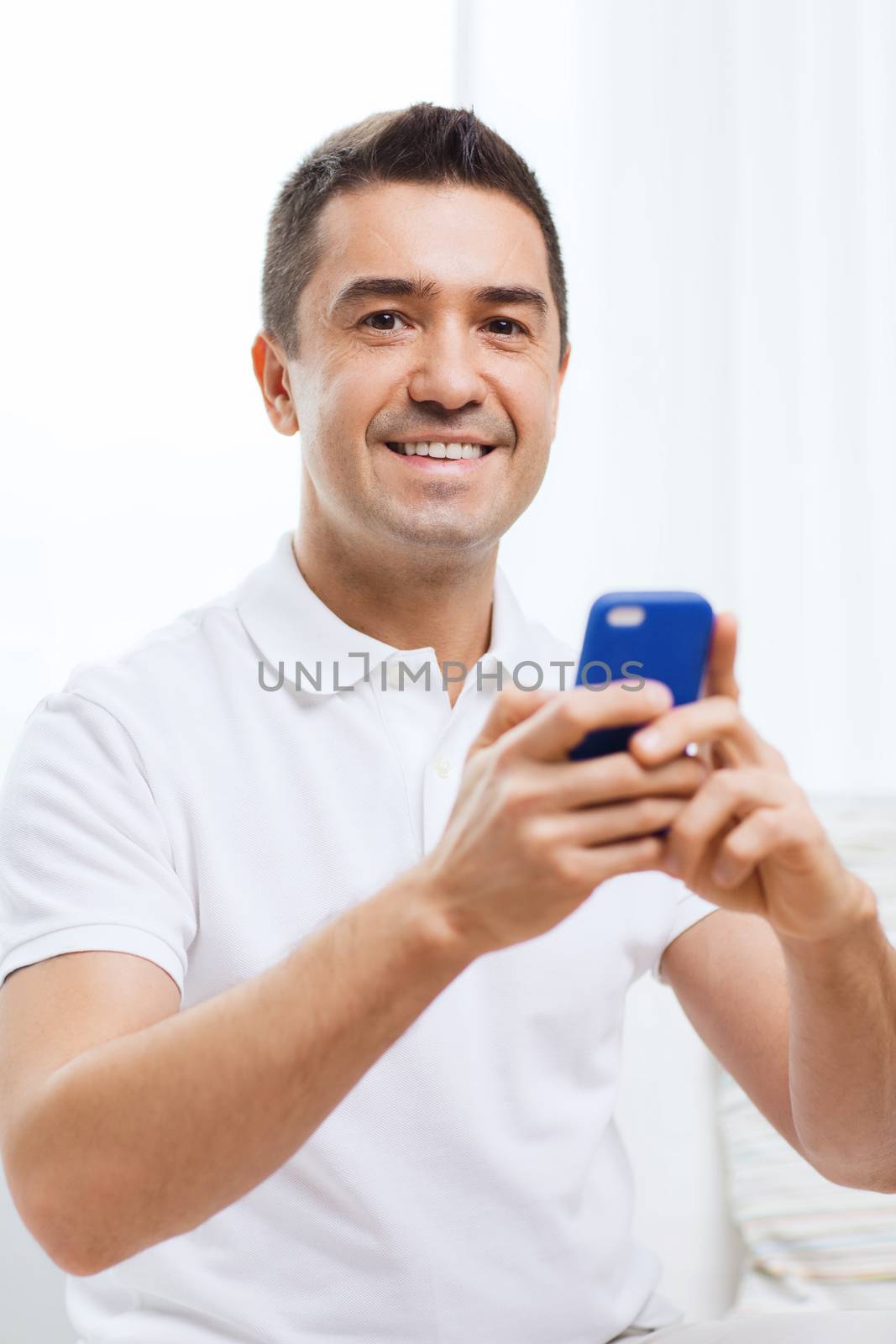technology, people, lifestyle and communication concept - happy man with smartphone at home