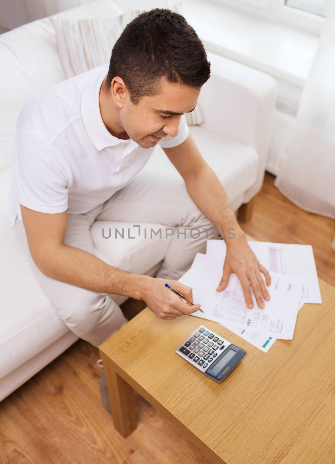 man with papers and calculator at home by dolgachov