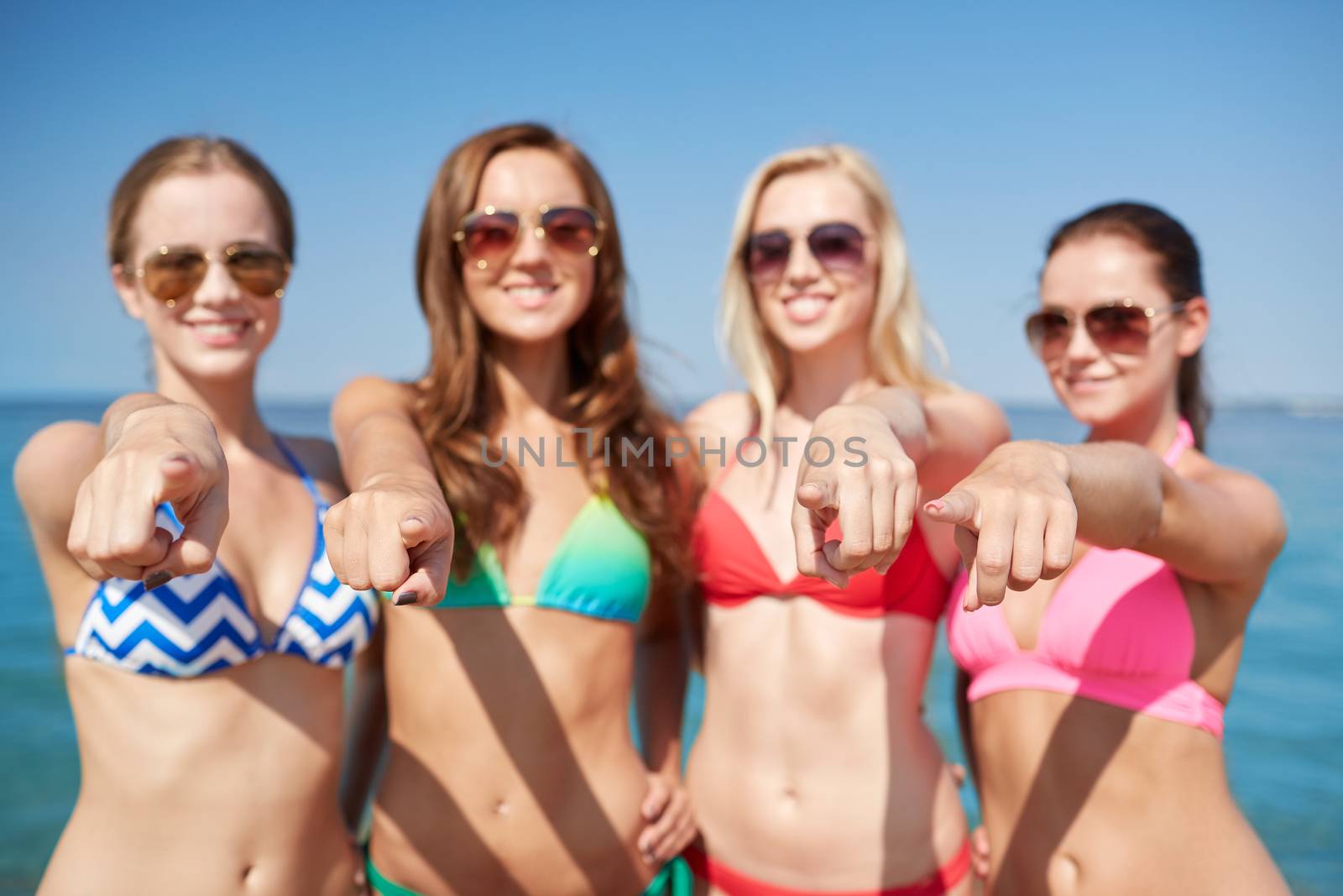 group of happy women pointing at you on beach by dolgachov